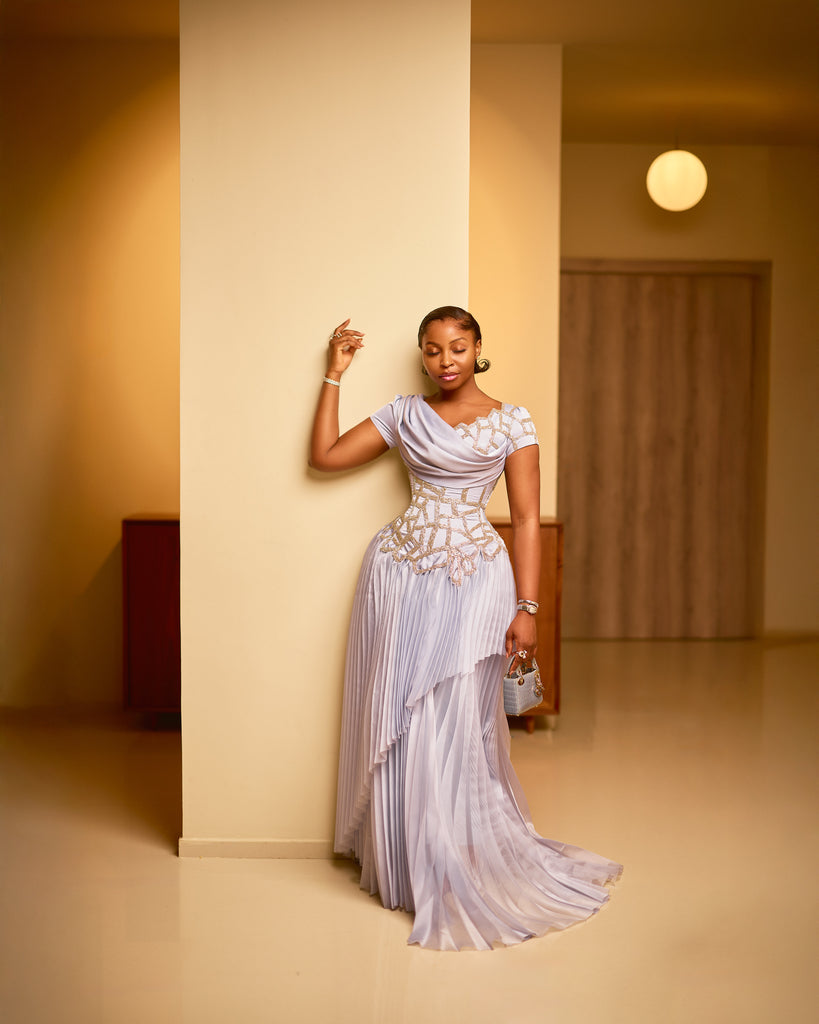 Model in ivory sculpted corset dress with asymmetric pleats and hand-beaded detailing.